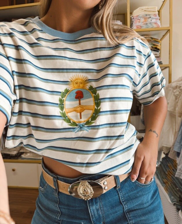 REMERA RAYADA CELESTE ESCUDO